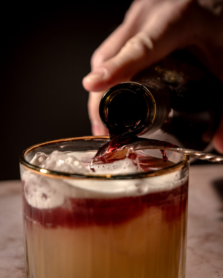 New York Sour cocktail featuring red wine layer atop a golden whiskey base