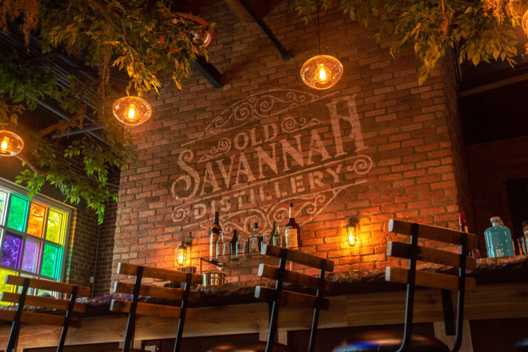 Old Savannah Distillery setting with whiskey bottles, greenery and warm lights