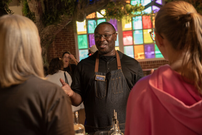 Bartender engaging guests with drinks in lively colorful old savannah distillery bar