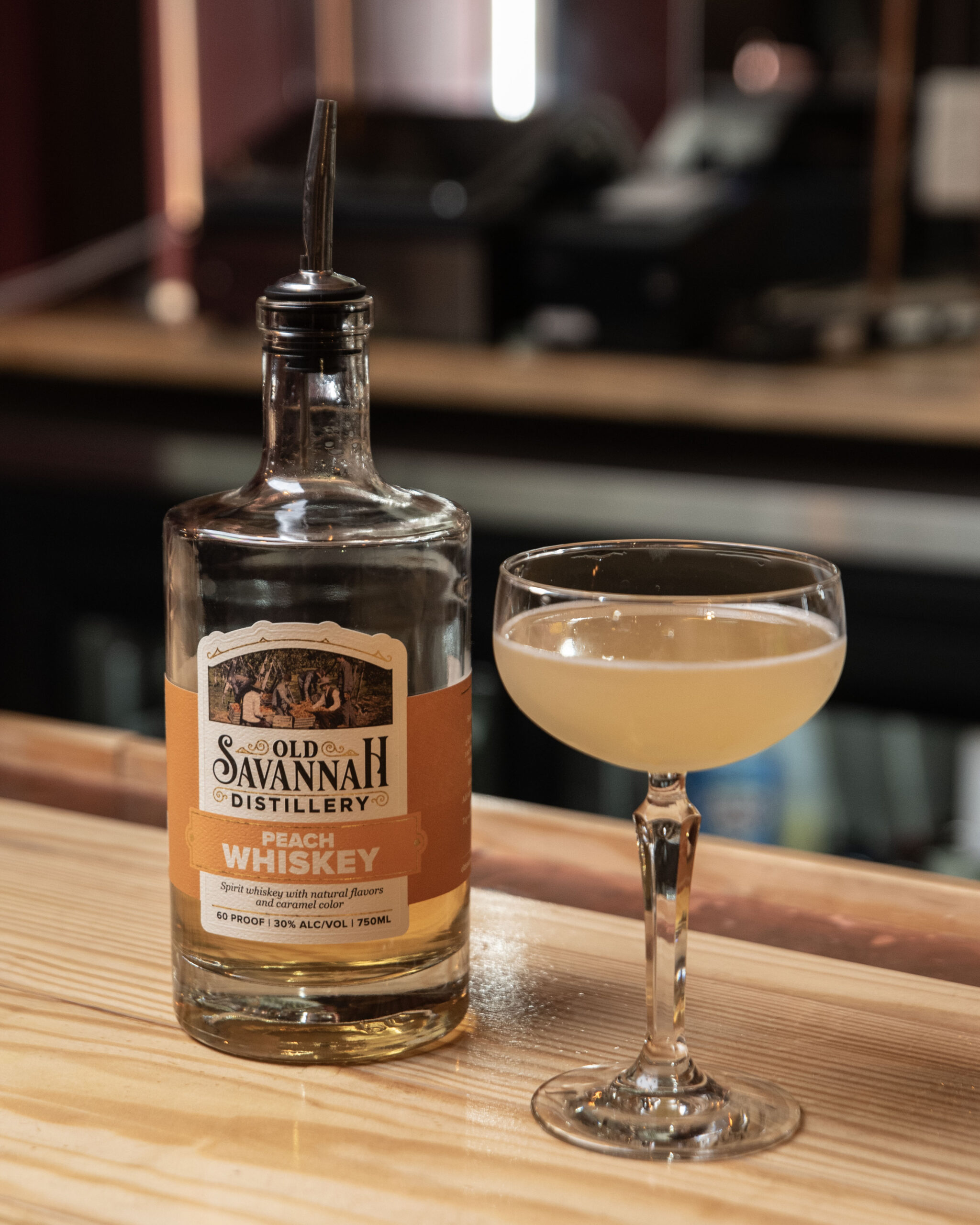 Old savannah distillery peach whiskey bottle with cocktail on bar counter.